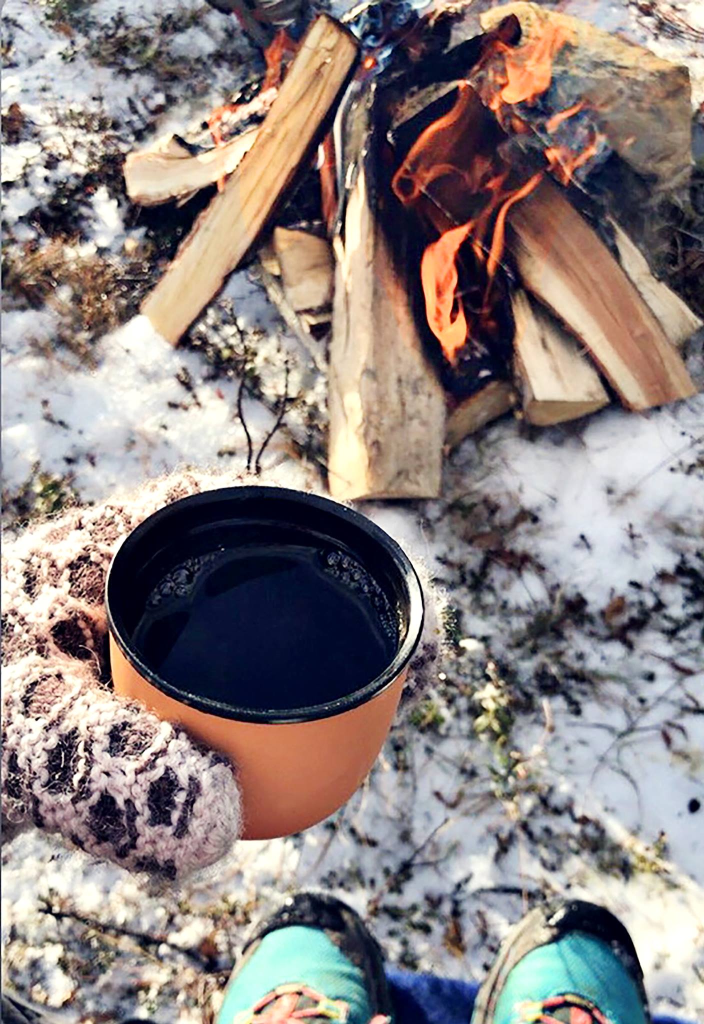 Kopp med kaffe fremfor bål på snødekt bakke