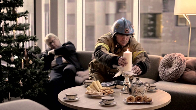 Brannkonstabel sitter i sofa på julekvelden og passer på et levende lys
